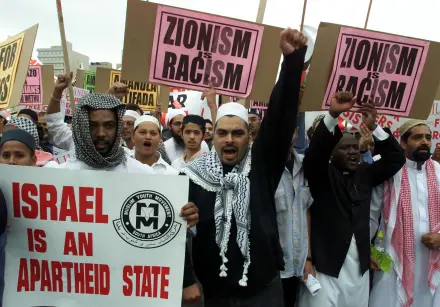 Palæstinensere protesterer med skilte, der siger Israel er en apartheidstat.